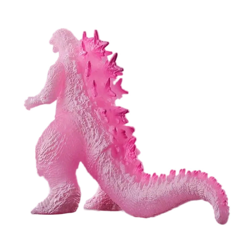 Pink Godzilla figurine on a reflective surface with a gray background